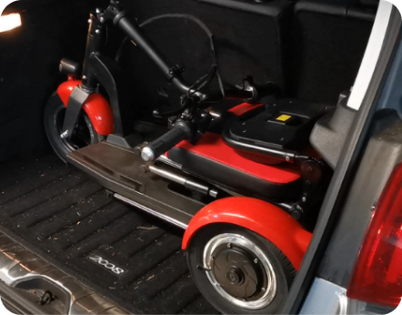 A red mobility scooter folded into the back of a vehicle