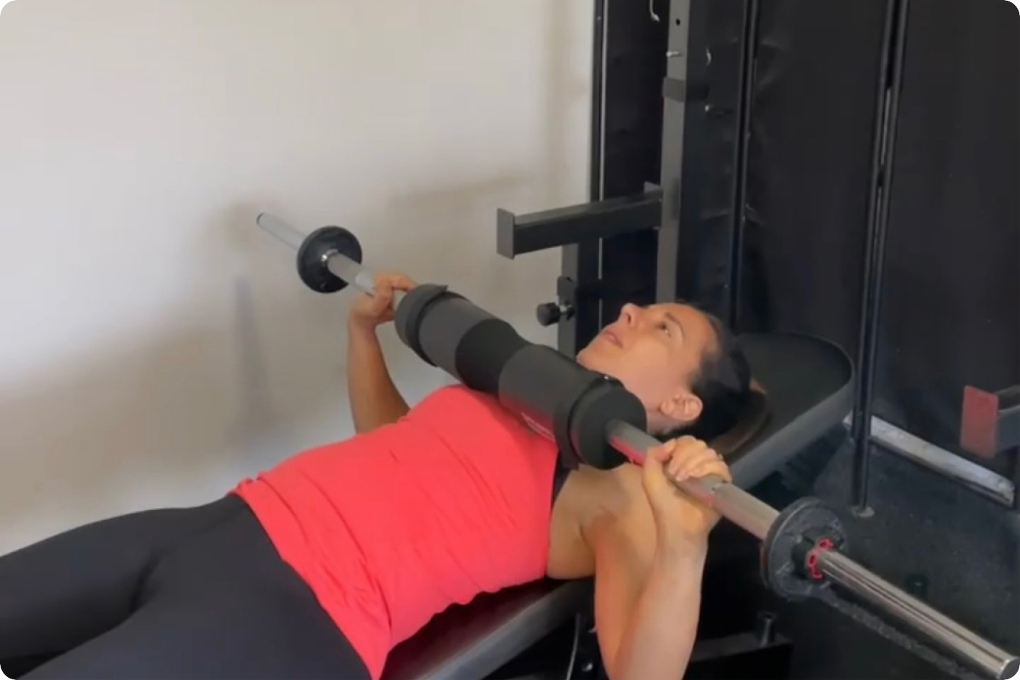 Photo of Georgina laying on an exercise bench doing a chest press with weights