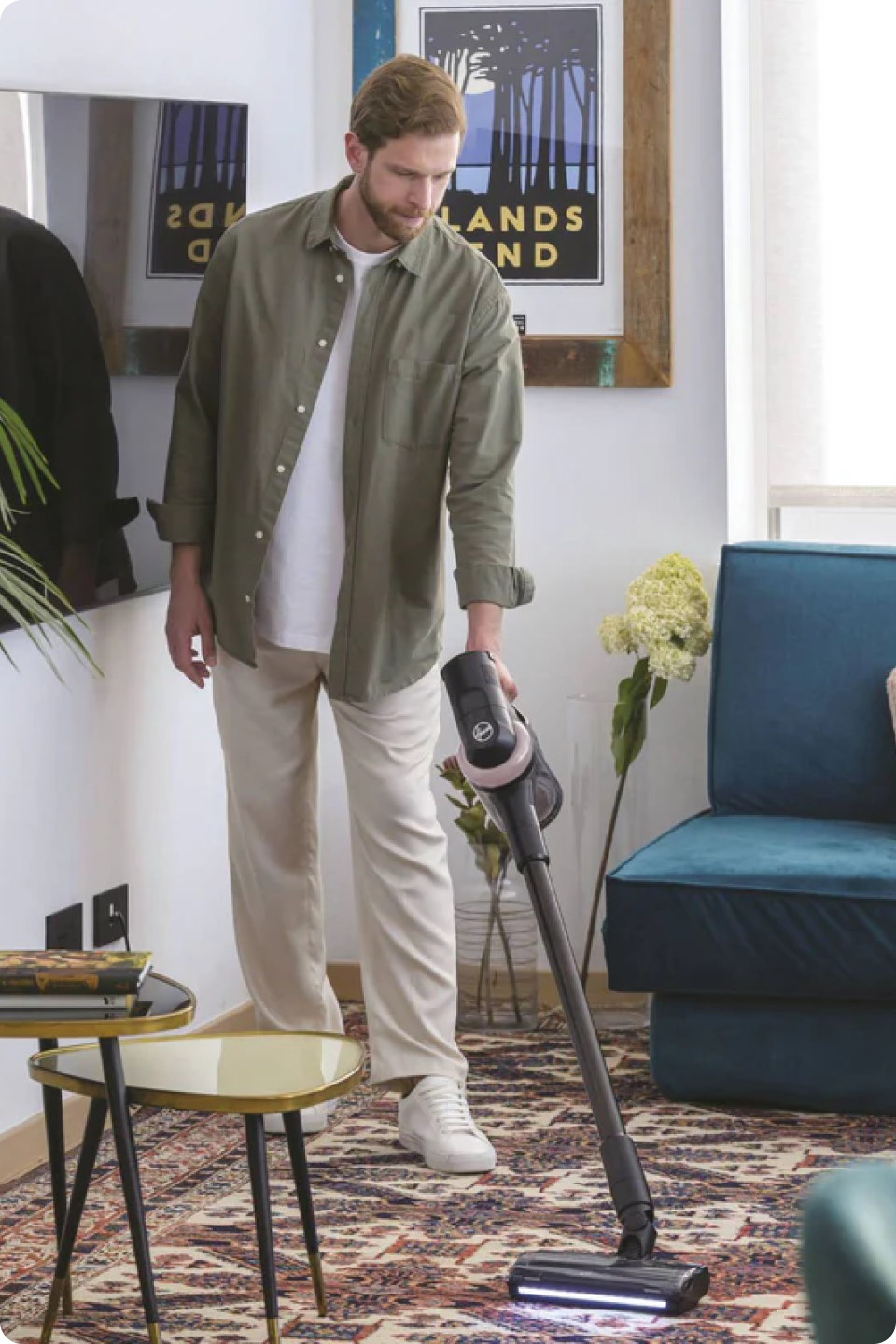 A man using the Hoover Cordless Vacuum Cleaner with Anti Hair Wrap - HF4: Special Edition in his lounge