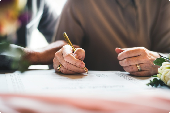 Two people sat, one is holding a pen and filling in paperwork