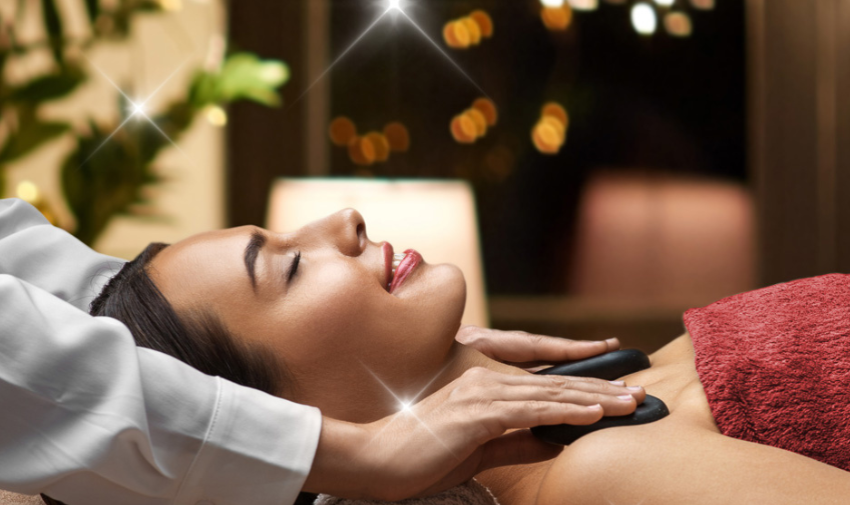 A woman receiving a hot stone massage with twinkly lights in the background