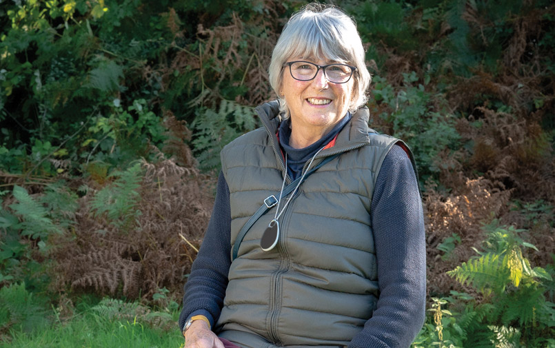 An older lady in a green gilt wears a personal alarm around her neck