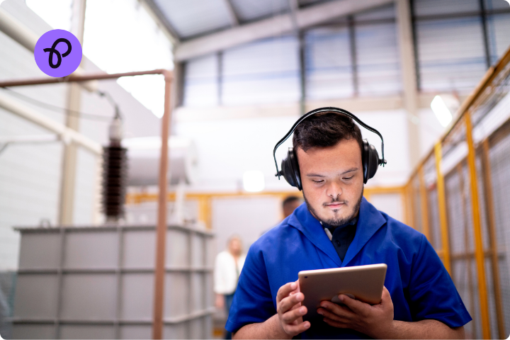 a man wearing ear protectors works in a warehouse, he has brown hair a blue shirt and looks as though he has learning disabilities