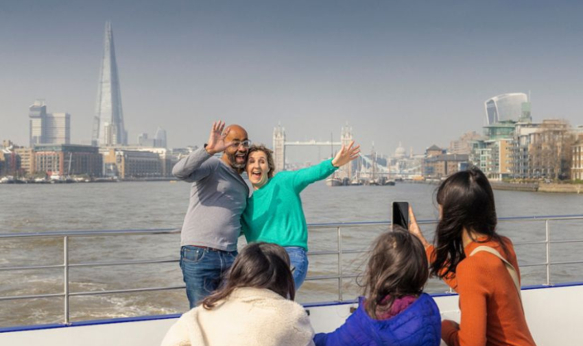 Man and woman waving to camera on a boat cruise in London City Cruises discount codes