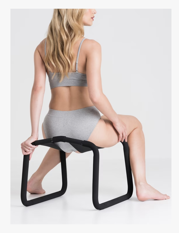 The Lovehoney Bondage boutique sex position enhancer chair with a woman sat on it with long blonde hair and grey underwear