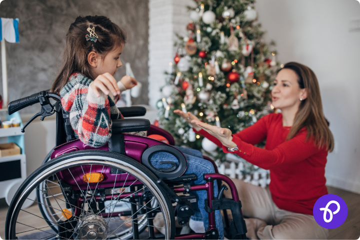 A mum and daughter who is a wheelchair user by a christmas tree