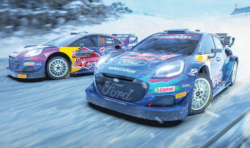 Two race cars that are blue and covered in ad stickers, there is the red bull logo and signs like castor, pulse and ford. Both cars look like they are racing on a snowy road