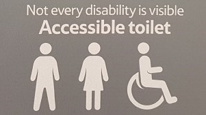 A toilet sign with the icon for male, female and wheelchair user and the text Not every disability is visible, accessible toilet