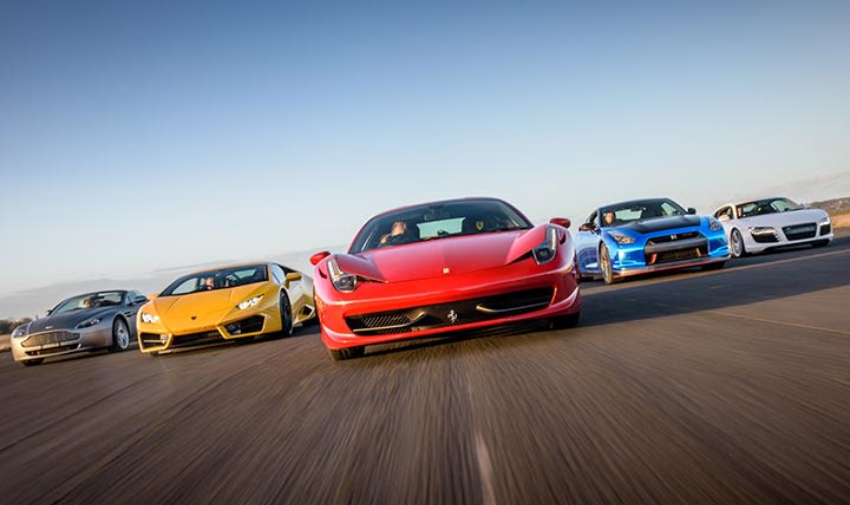 five sports cars on a track, silver, yellow, red, blue, white.