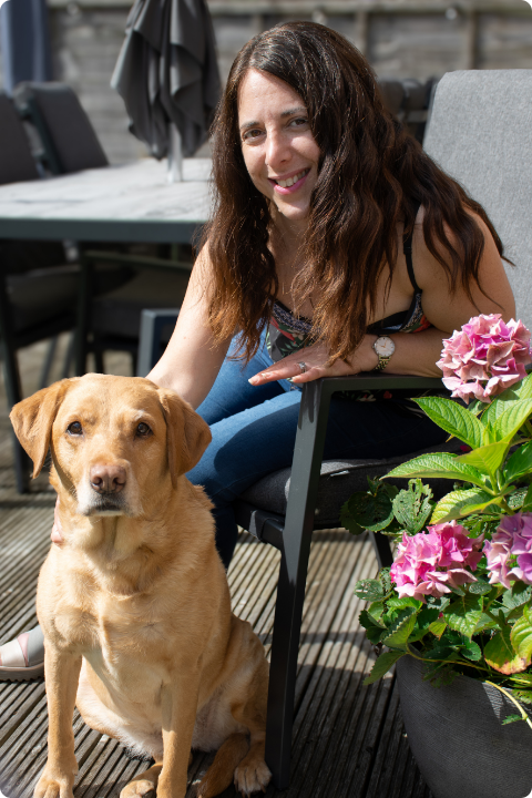 Georgina in her garden sat on a chair with her yellow labrador posing next to her.