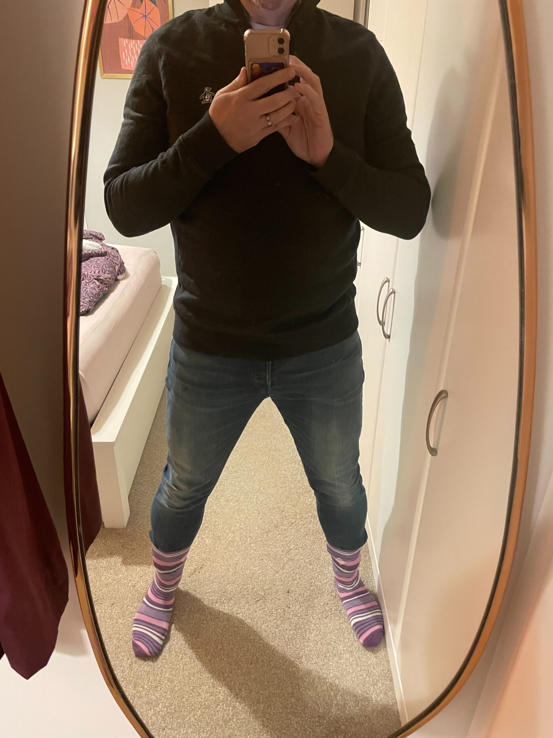 A man poses in a mirror in jeans and a dark top with purple stripy socks, you cant see his face celebrating Purple Sock Day for the International Day of Disabled People 