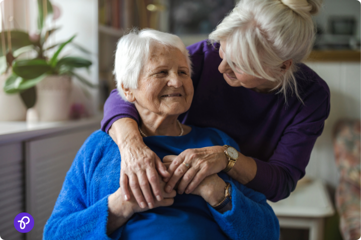 Elderly woman and caregiver embracing, representing care and financial assistance for disabled seniors.