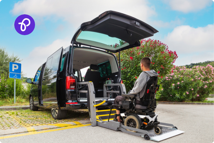 A male wheelchair user is using a lift to get into the rear of a mobility car adapted for wheelchair use