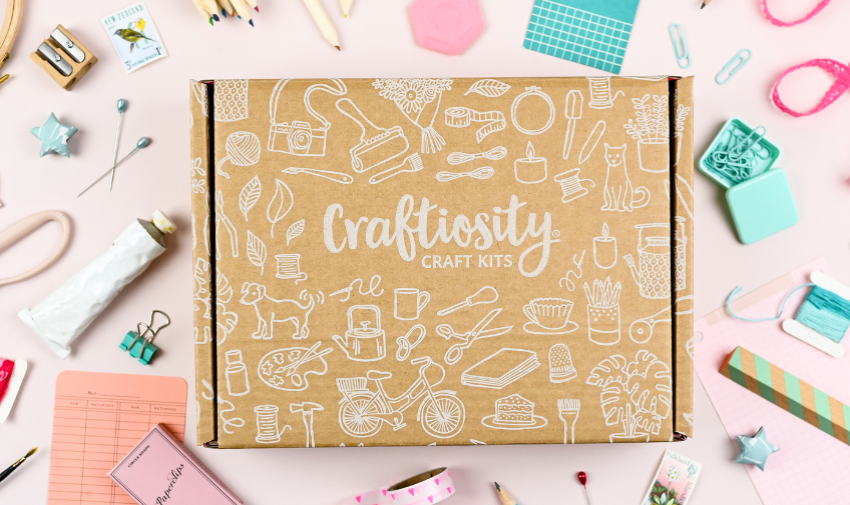 a brown box with craftiosity craft kits written on it, surrounded by lots of different craft items