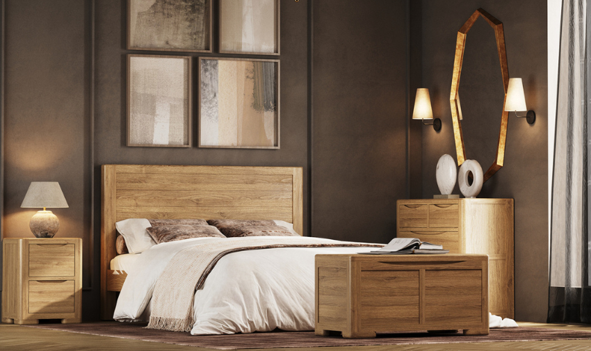 A bedroom scene with an oak bed, bedside table, drawers and a chest. The room is painted in a taupe grey and there is cream bedding on the bed, the room looks natural and calm