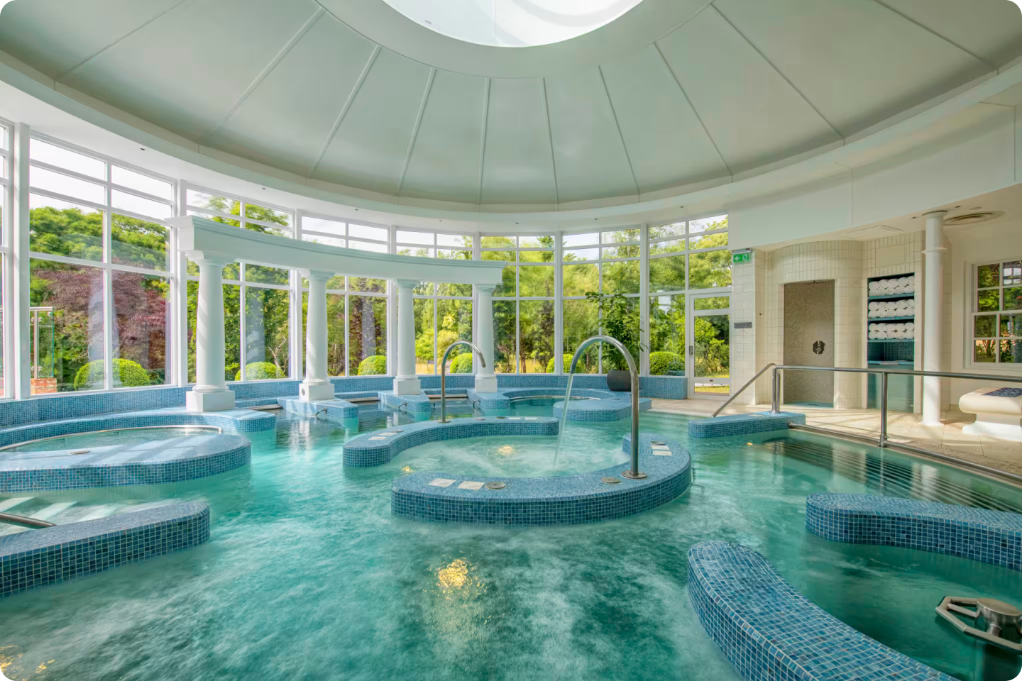 A spa with lots of jacuzzis in one pool area, with lots of blue mosaic tiles, it looks calm and luxurious 