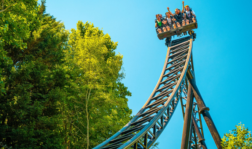 A rollercoaster at Thorpe Park on a sunny day with blue skies and gree trees behind