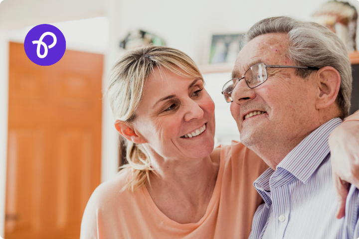 A woman has her arm around the shoulders of an older man in a caring gesture